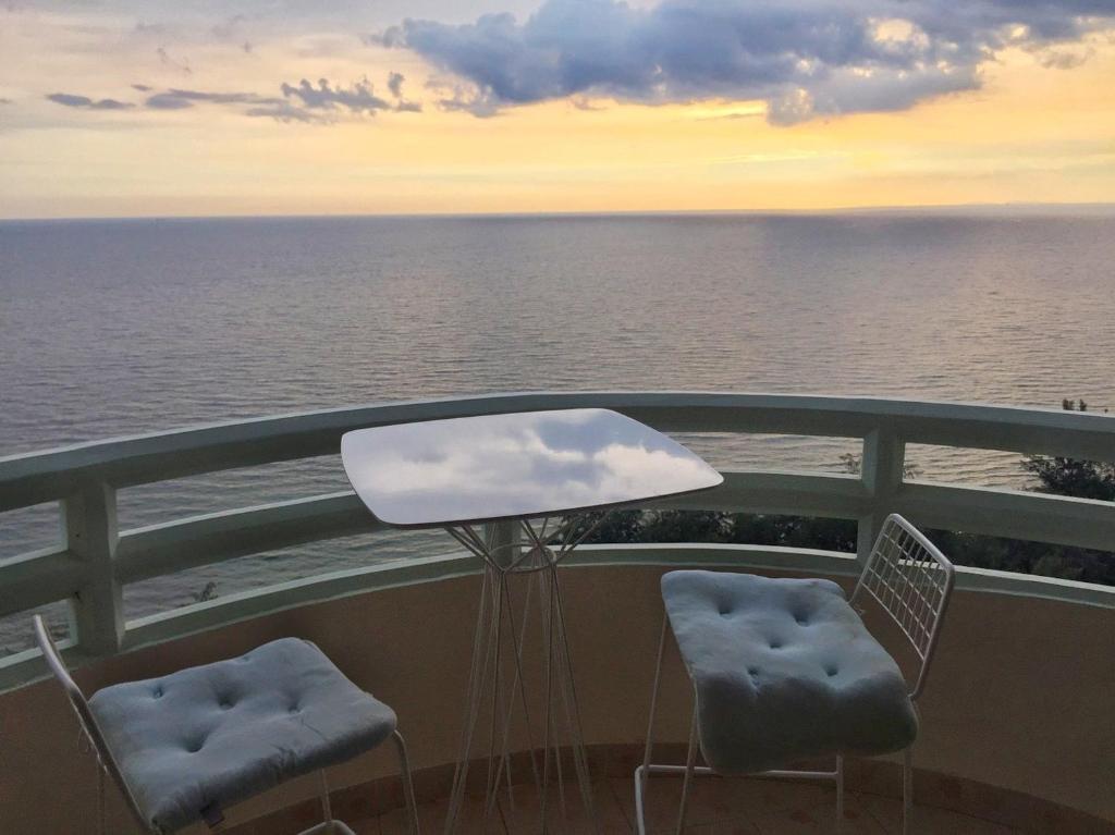 班佩雷农贵宾公寓的俯瞰大海的阳台配有两把椅子和一张桌子
