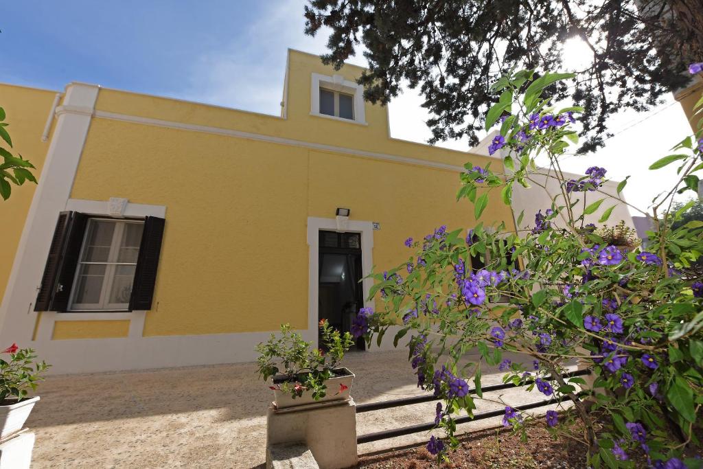 蒙塔尔巴诺Villa Ricciardi-Suite famigliare 1-zona Ostuni的黄色房子前面有紫色的花