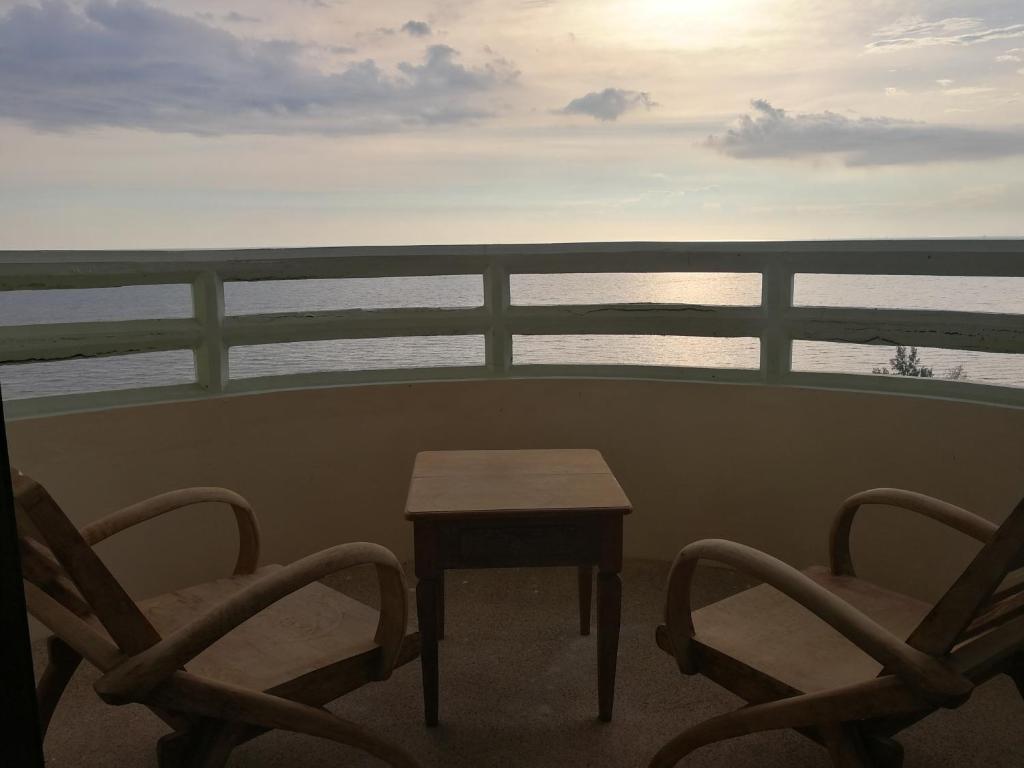 班佩罗勇市泰式风格VIP公寓的阳台上配有两把椅子和一张桌子,享有海景