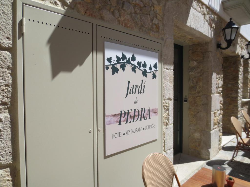 莱斯卡拉Jardi de Pedra的门上的标牌,上面有桌椅