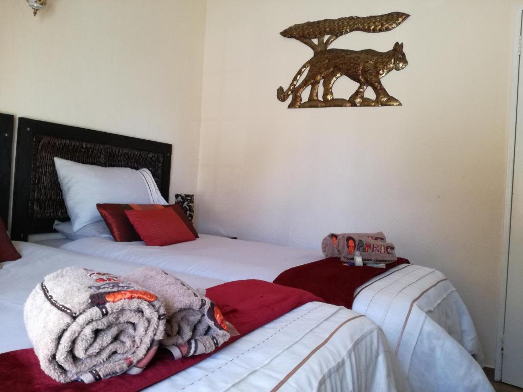 肯普顿帕克All over Africa Guest house的一间卧室设有两张床,墙上有狼雕像