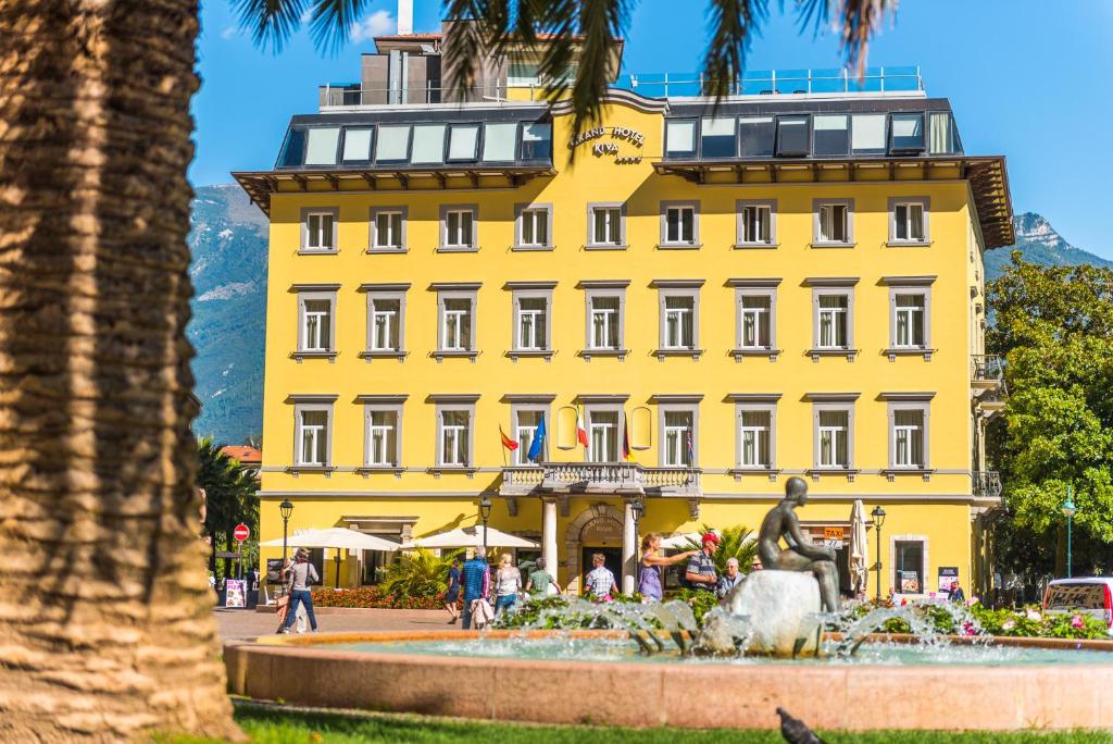 加尔达湖滨里瓦大酒店的一座黄色的建筑,前面有一个喷泉