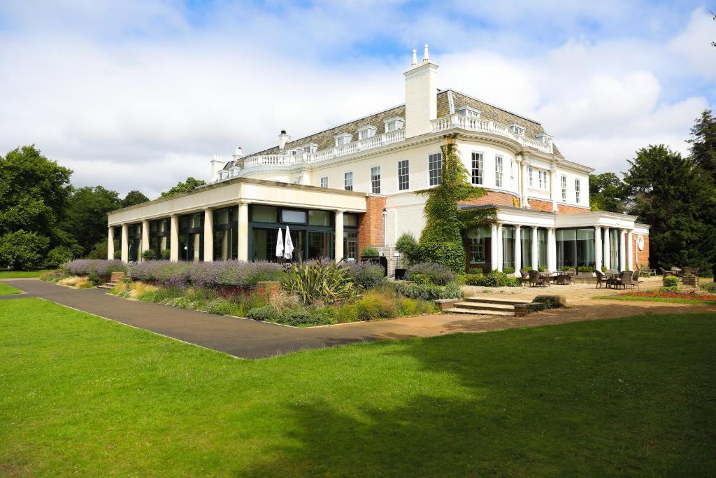 伦敦温布尔登杜文堪尼扎罗之家酒店的一座白色的大建筑,设有绿色草坪