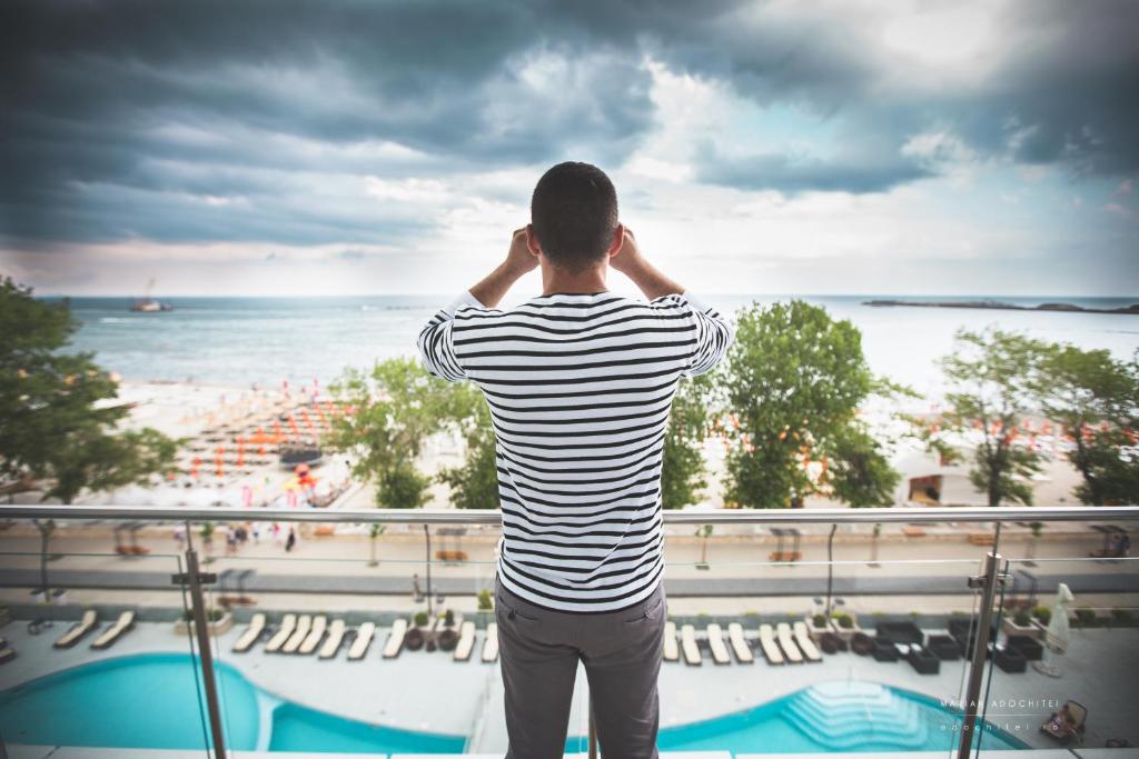 马马亚巴伐利亚布鲁酒店的站在海滩上的阳台上的人