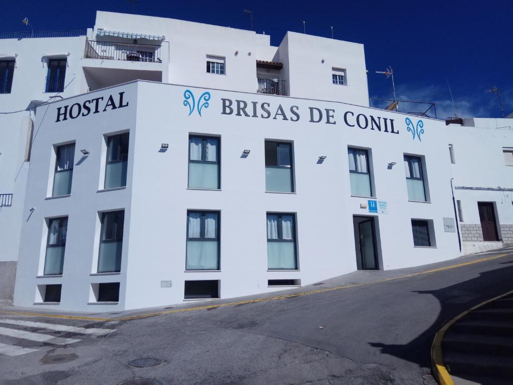 科尼尔-德拉弗龙特拉Hostal Brisas de Conil的白色的建筑,上面写着“Brizas de council”的字样