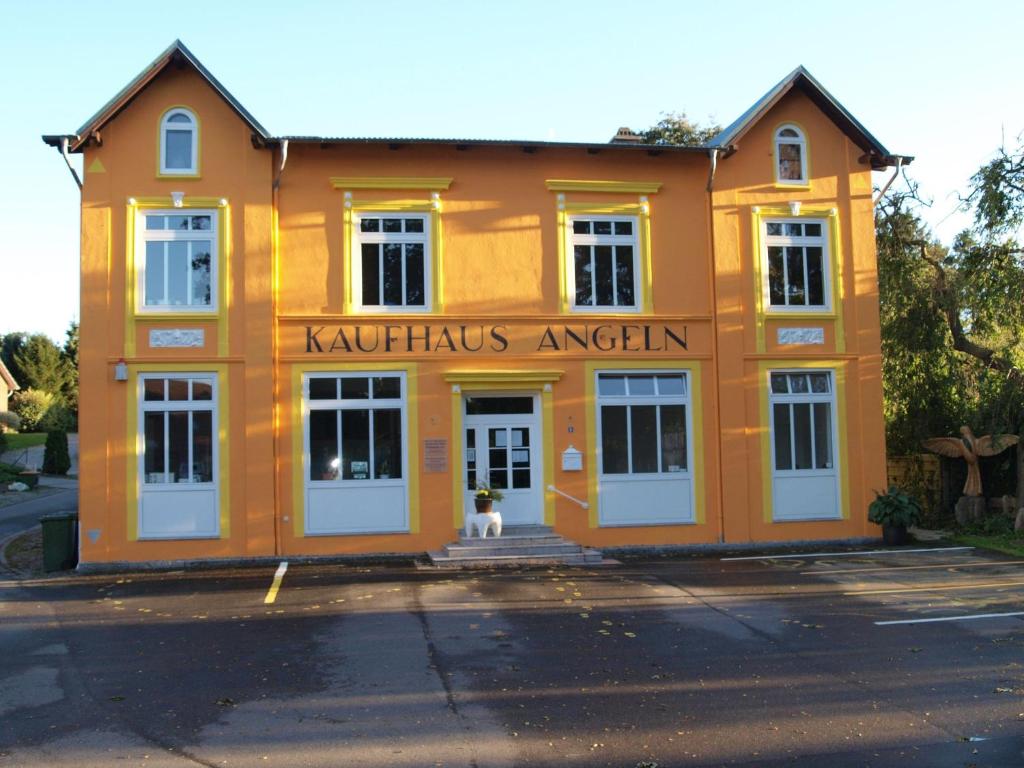 SterupFerienwohnung-im-historischen-Kaufhaus-Angeln的一座橙色的建筑,门口就有一个狗