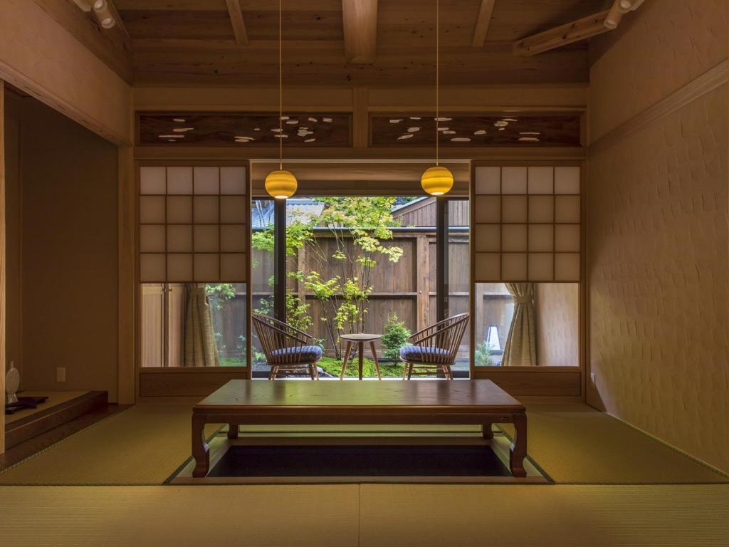 Totsukawa仙景汤乃谷日式旅馆的客房设有桌子、两把椅子和窗户。