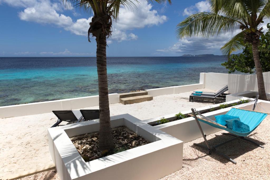 克拉伦代克One Ocean Boutique Apartments & Suites Bonaire的海滩上的棕榈树和吊床