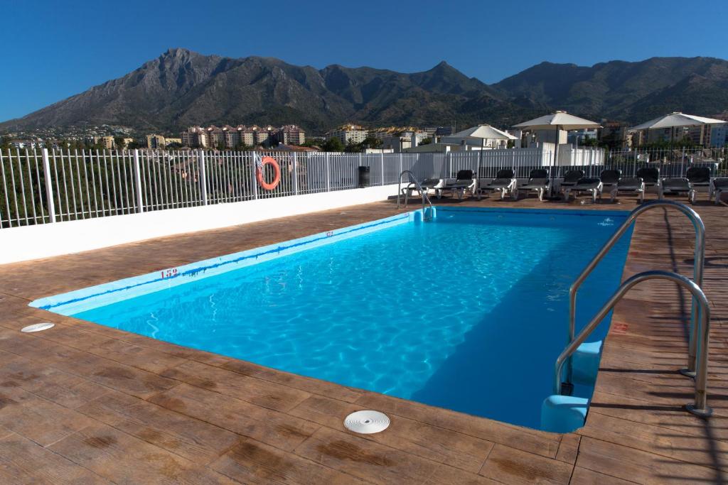 马贝拉Ona Marbella Inn的一个带椅子的游泳池,背景是山脉