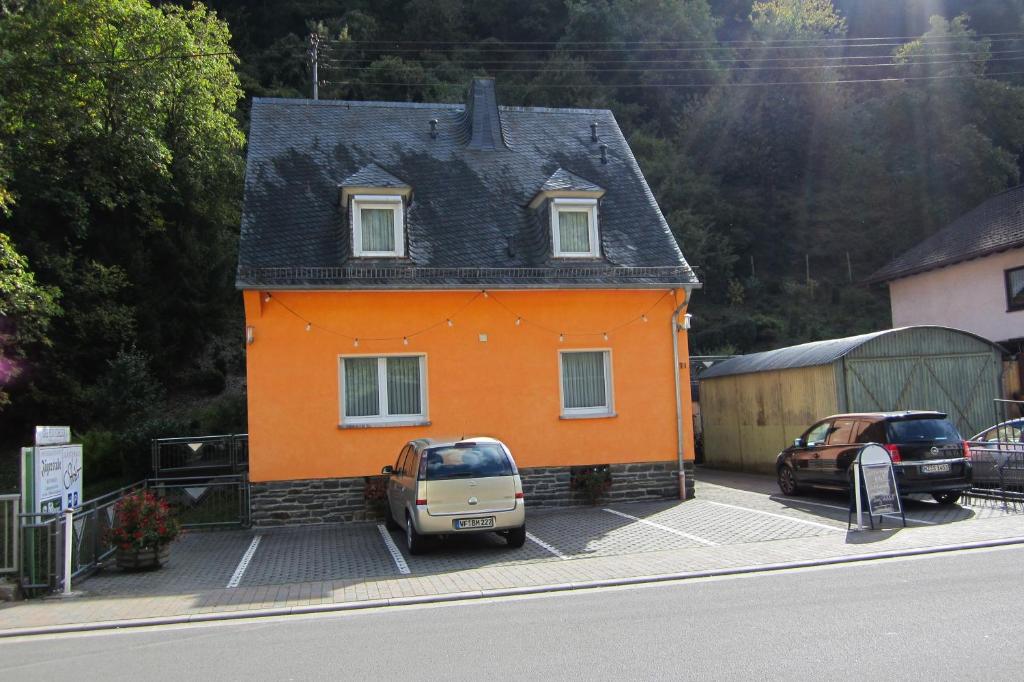 巴哈拉赫斯特罗特尔旅馆的一座小型橙色房子,前面有汽车停放