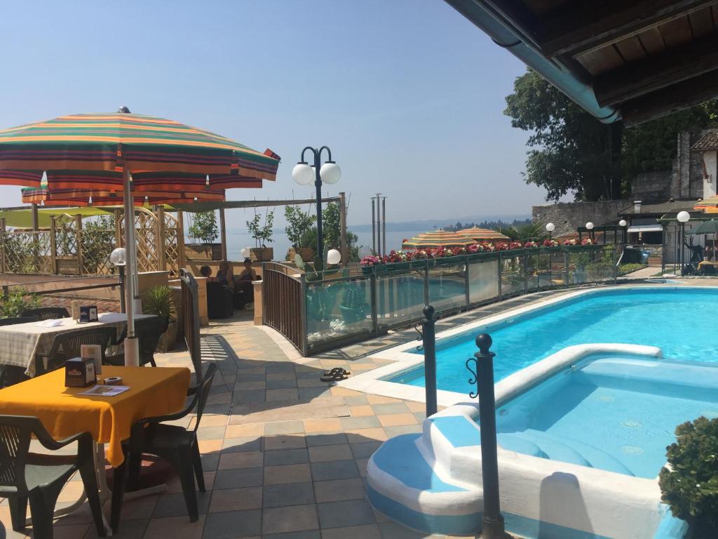 托斯科拉诺-马德尔诺Garda Sol SPA Hotel & Appartamenti的一个带桌子和遮阳伞的游泳池