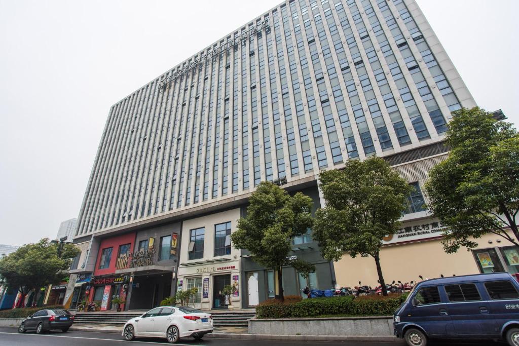 常州锦江都城常州恐龙园新北万达广场酒店的一座大型建筑,前面有汽车停放