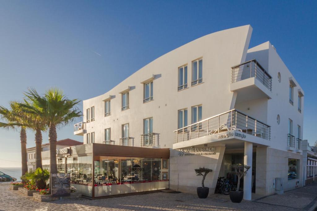 萨格里什马雷塔海滩 - 精品住宿&早餐酒店的一座白色的大建筑,前面有一棵棕榈树