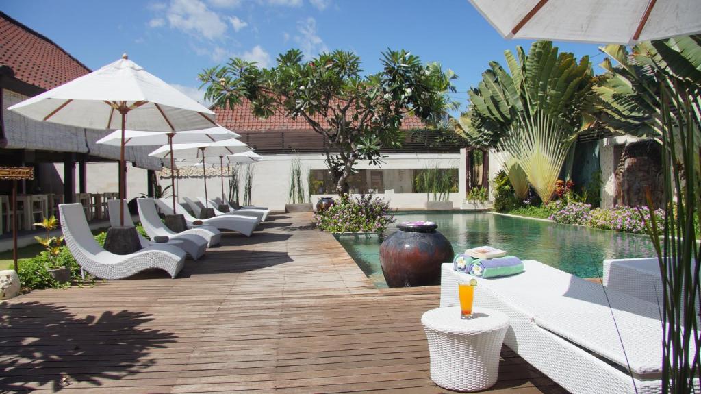 沙努尔Katala Suites and Villas的一个带白色躺椅和遮阳伞的游泳池