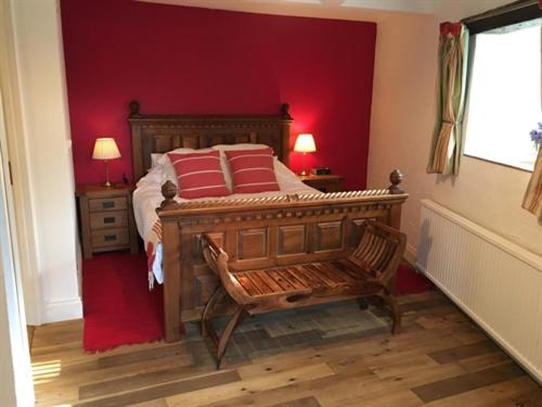 谢伯恩斯通谷仓住宿加早餐旅馆的一间卧室设有一张木床和红色的墙壁