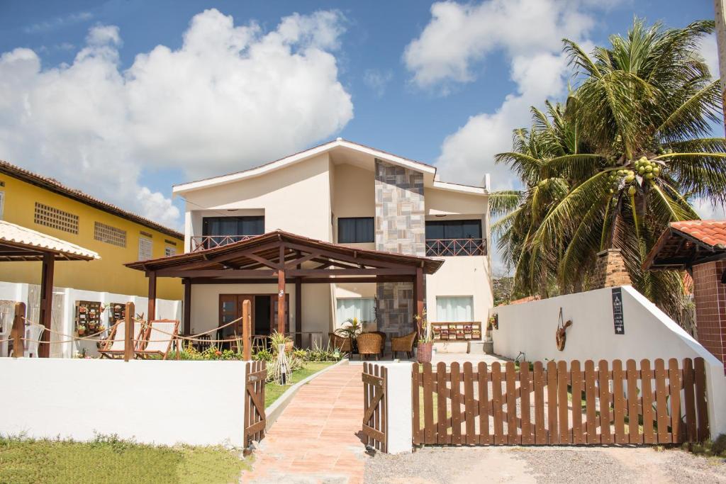 伊塔马拉卡Pousada Nossa Ilha的白色围栏和棕榈树的房子