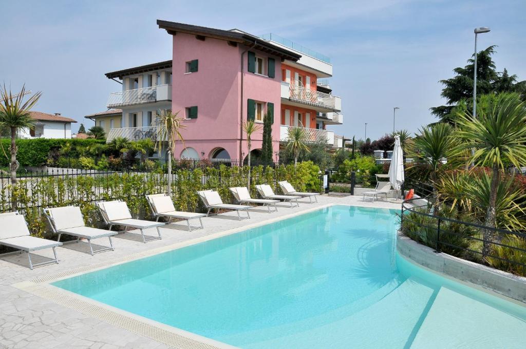 西尔米奥奈阿昌泉度假酒店的一座带椅子的游泳池以及一座粉红色的建筑
