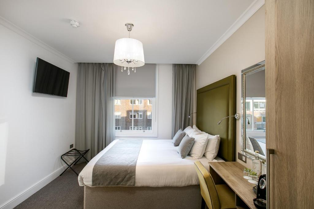 伦敦公园大道海德公园J酒店的一间卧室配有一张床、一张书桌和一个窗户。