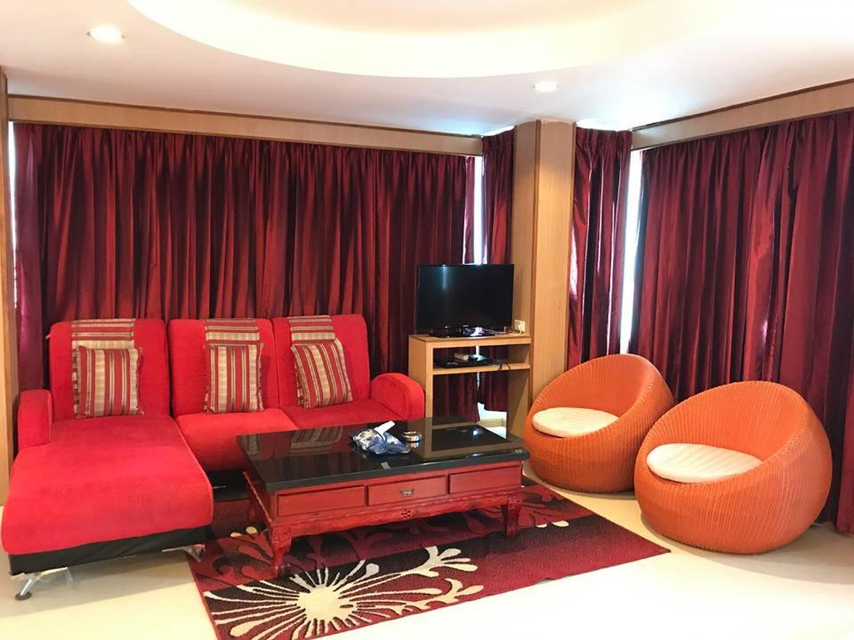 芭堤雅市中心星居酒店的客厅配有红色的沙发和两把椅子