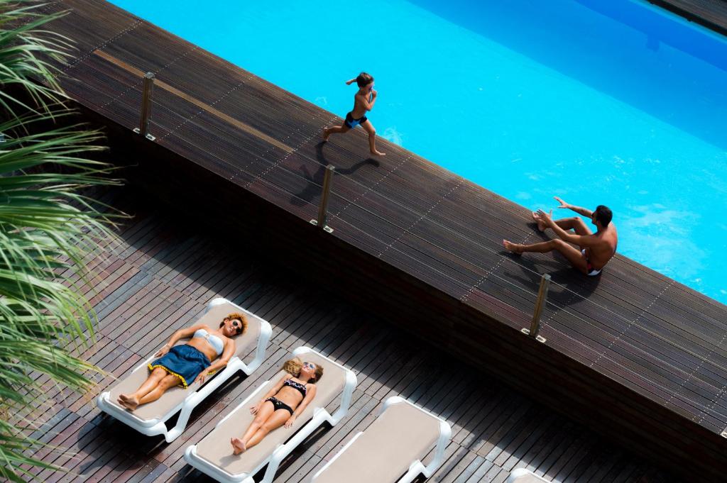 里乔内Hotel Lido Europa的一群人坐在游泳池旁的躺椅上