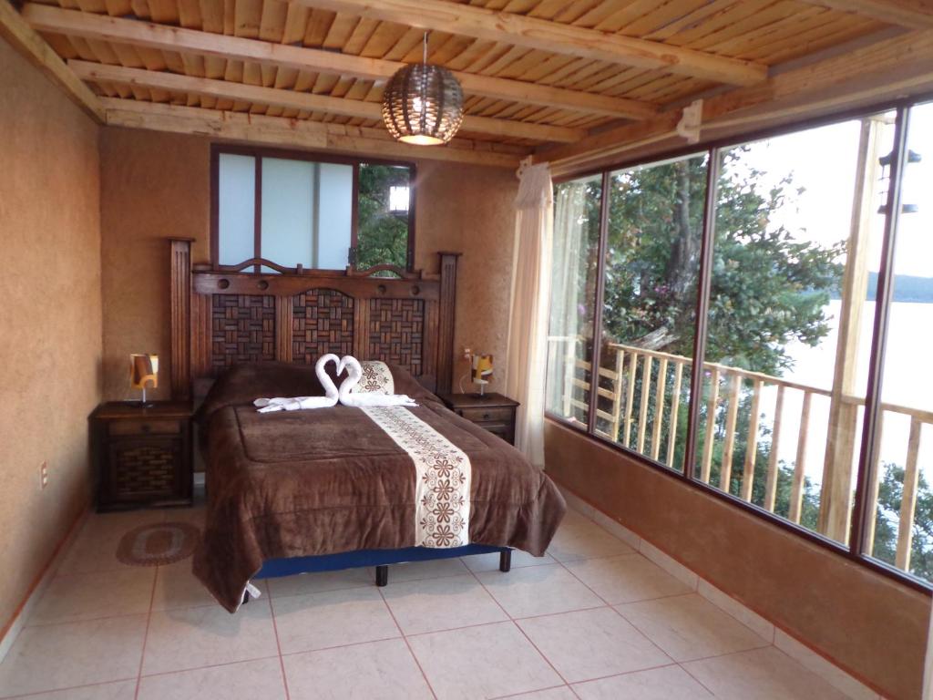 兹拉胡恩ZIRAHUÉN CUIN Habitaciones Rústicas的一间卧室配有一张床,阳台配有窗户