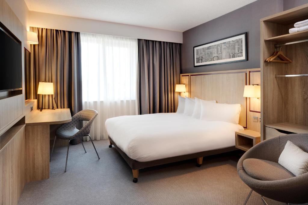 沃特福德Leonardo Hotel London Watford的酒店客房,配有一张床、一张桌子和椅子