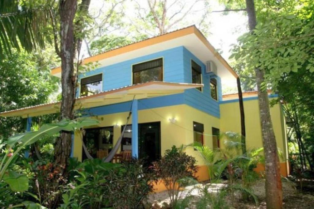 诺萨拉Nosara Paradise Rentals的森林中的蓝色和黄色房子