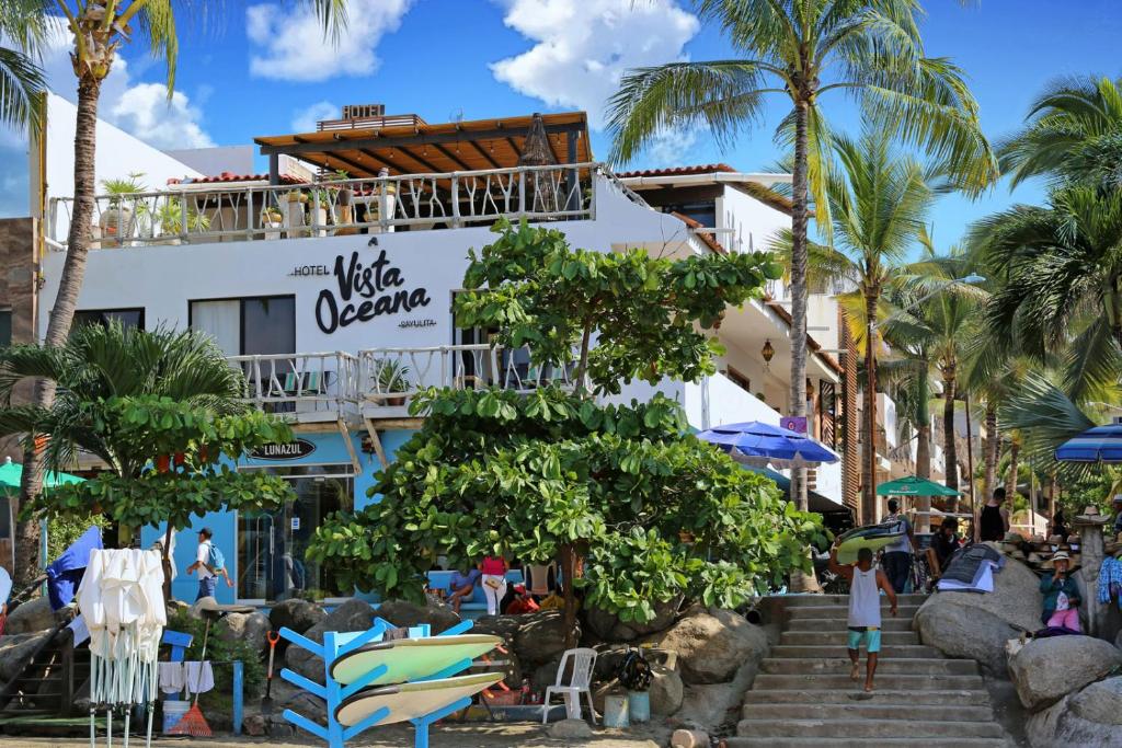 萨尤利塔Hotel Vista Oceana Sayulita的棕榈树和椅子的海滩上酒店