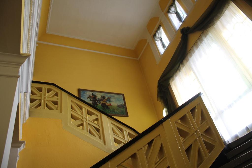 纳梅斯武夫珀洛尼亚酒店的走廊上设有黄色的墙壁和楼梯,墙上有绘画作品