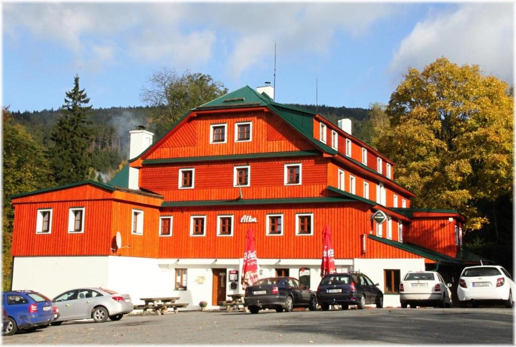 德尔内夫奥里克阿尔巴酒店的一座红色的大建筑,停车场有汽车停放