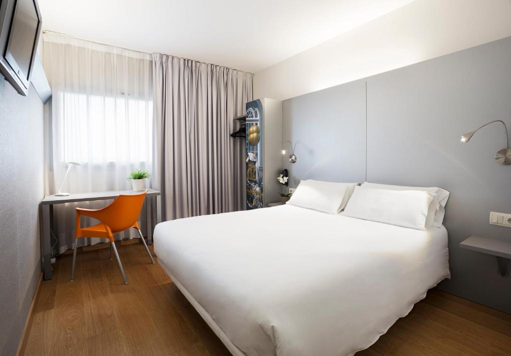 菲格拉斯B&B HOTEL Figueres的酒店客房设有一张白色大床和一张书桌