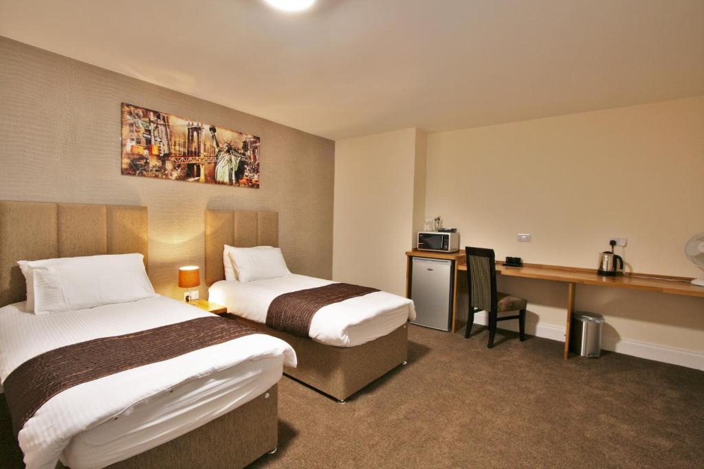 格洛斯特New County Hotel & Serviced Apartments by RoomsBooked的酒店客房配有两张床和一张书桌