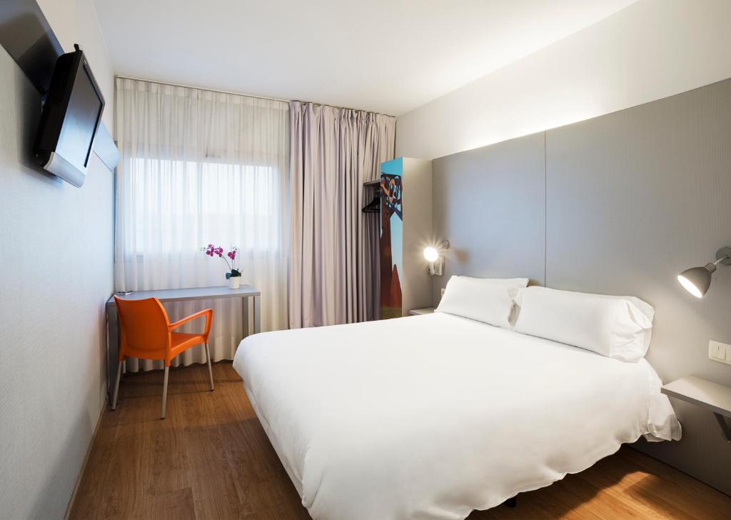 萨尔特B&B HOTEL Girona 2的酒店客房设有一张白色大床和椅子