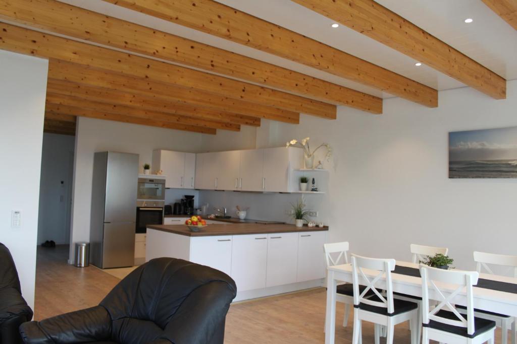 KollmarFerienwohnung Santore的厨房配有白色橱柜和木制天花板。