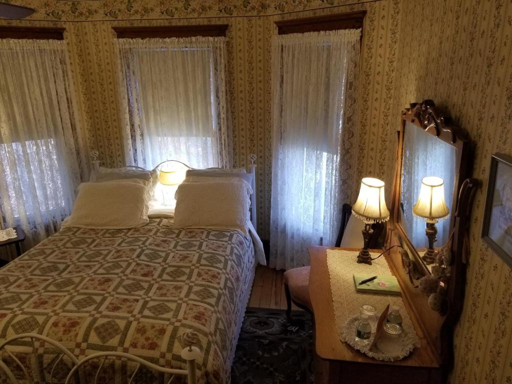 库珀斯敦Rose & Thistle Bed & Breakfast的一间卧室配有一张床和一张桌子上的两盏灯。