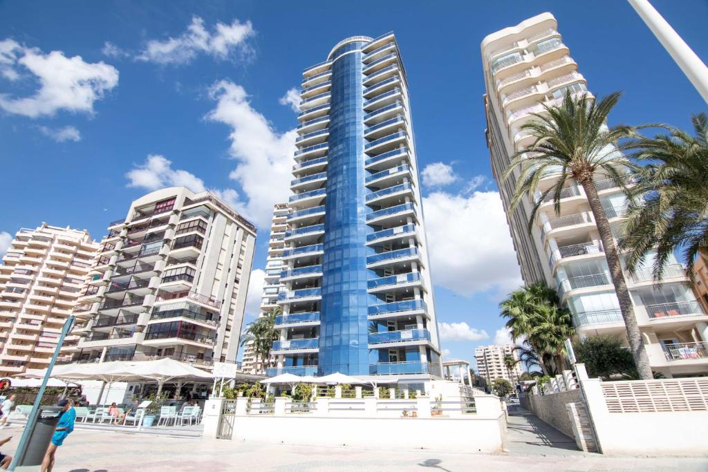 卡尔佩维斯塔贝拉公寓的海滩上一座高大的建筑,有棕榈树和建筑