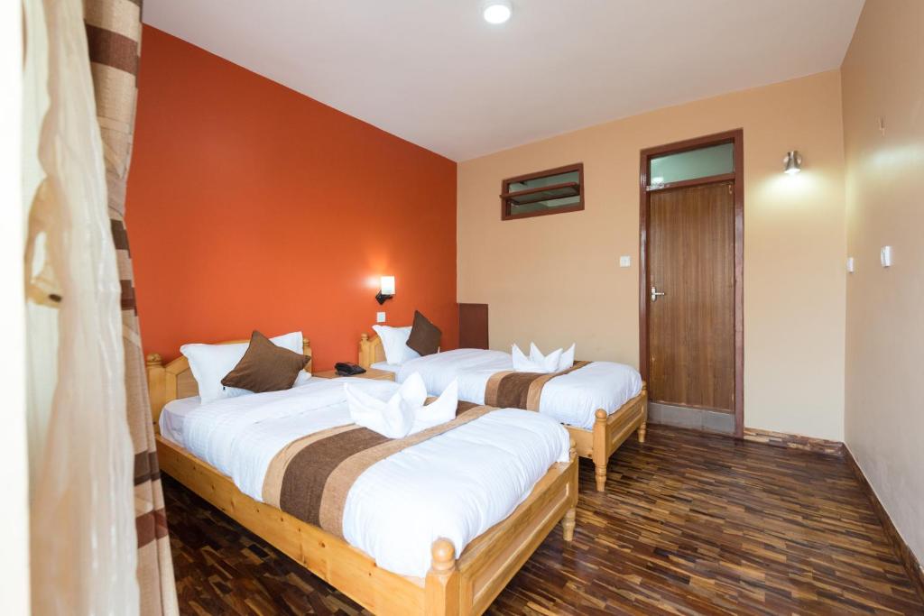 加德满都Khangsar Home的橙色墙壁客房的两张床