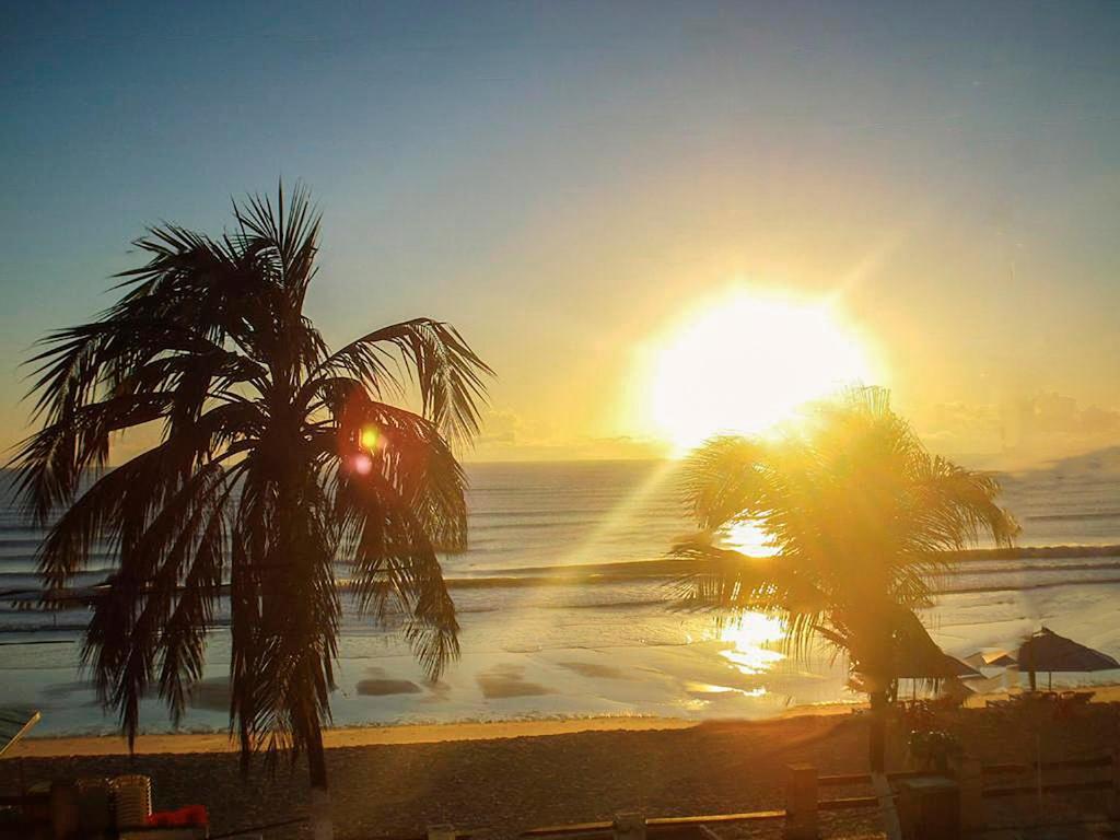 纳塔尔POUSADA TIA LUCY的两棵棕榈树海滩上的日落