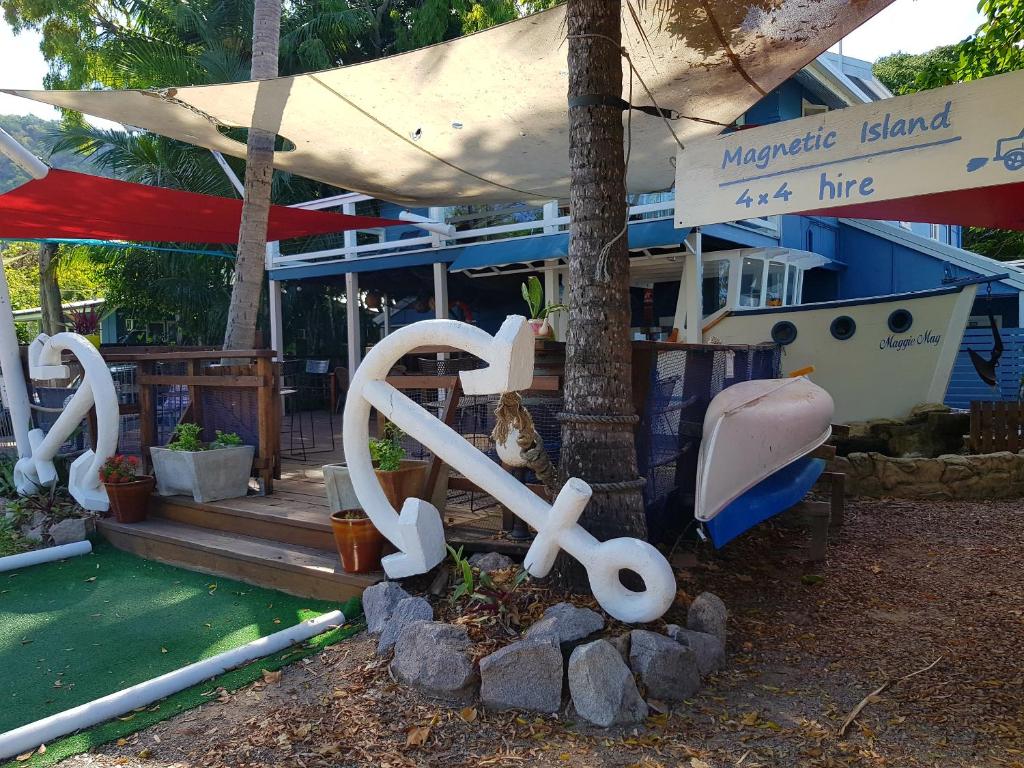 耐莉湾Arcadia Beach Guest House and Car Hire的坐在房子前面的长凳雕像