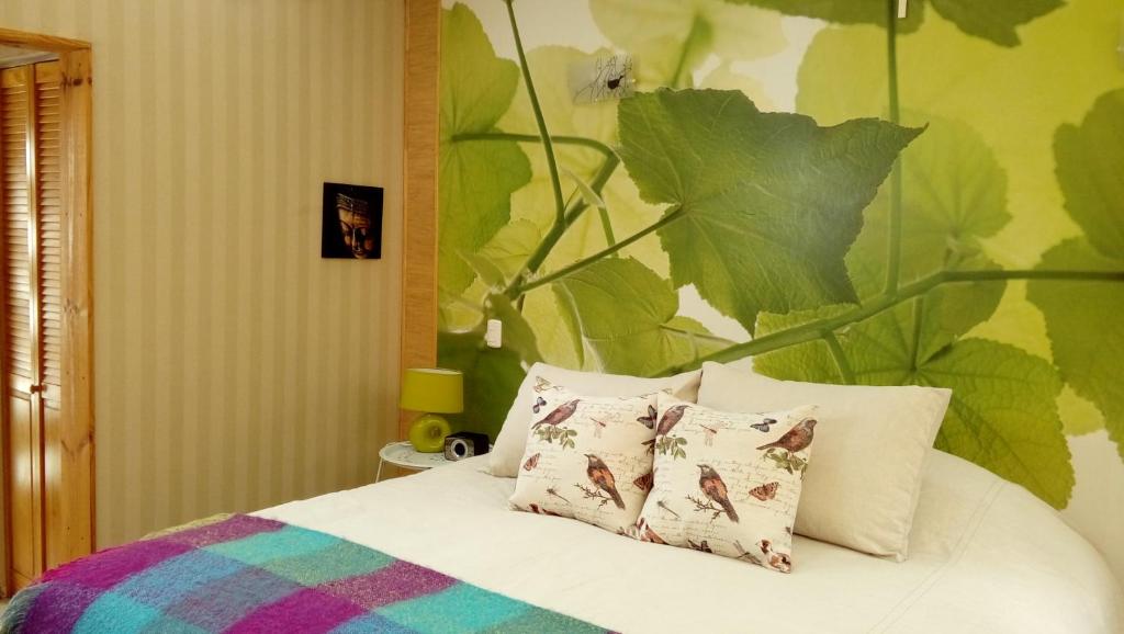 维库尼亚Organica Lodge Spa的一张带两个枕头的床和一个大叶墙