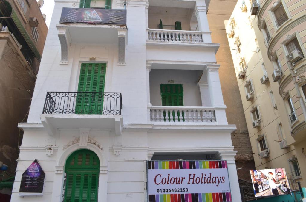 开罗Colour Holidays的白色的建筑,有绿色的窗户和标志
