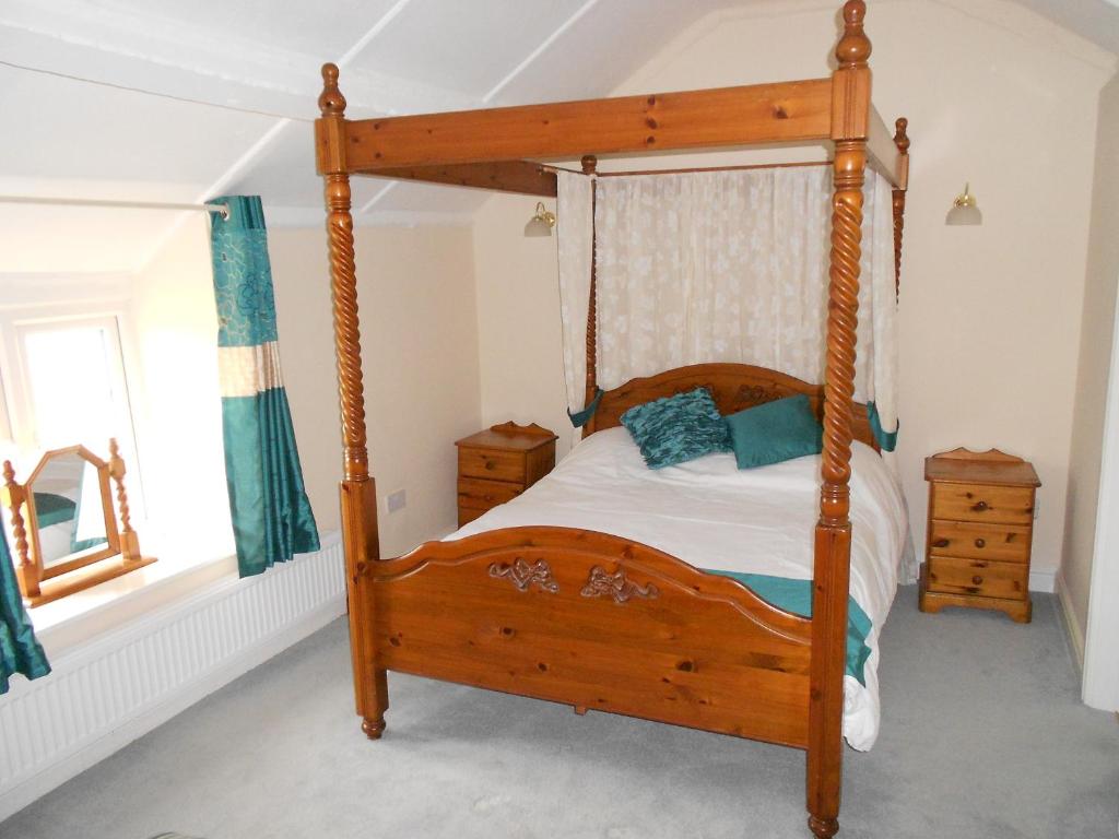 霍利韦尔格兰年阿丰旅馆的一间卧室配有一张木床和木架
