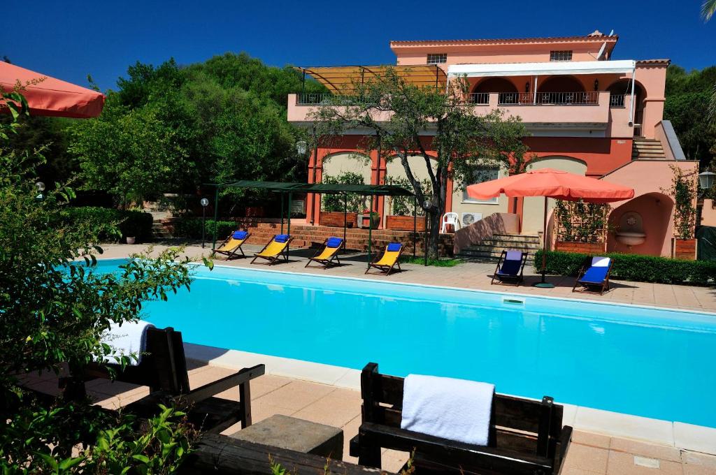 卡拉·利贝罗托Hotel Villa Campana的一座带椅子和遮阳伞的游泳池位于一座建筑旁边