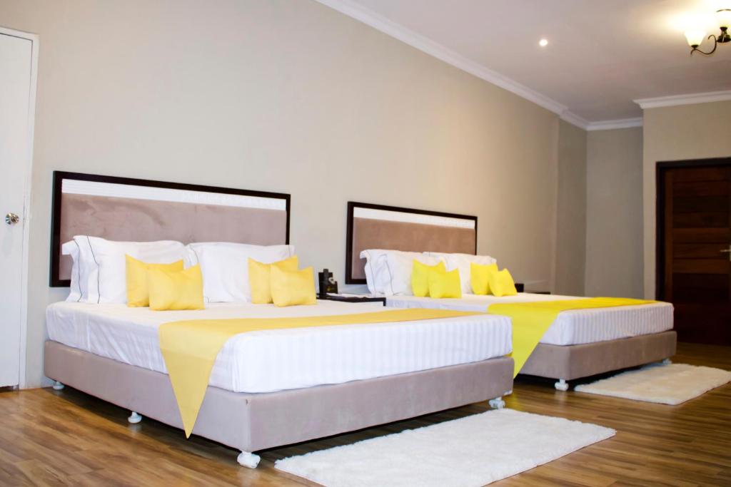 SengaBlue Waters by Serendib的卧室内的两张床和黄色枕头