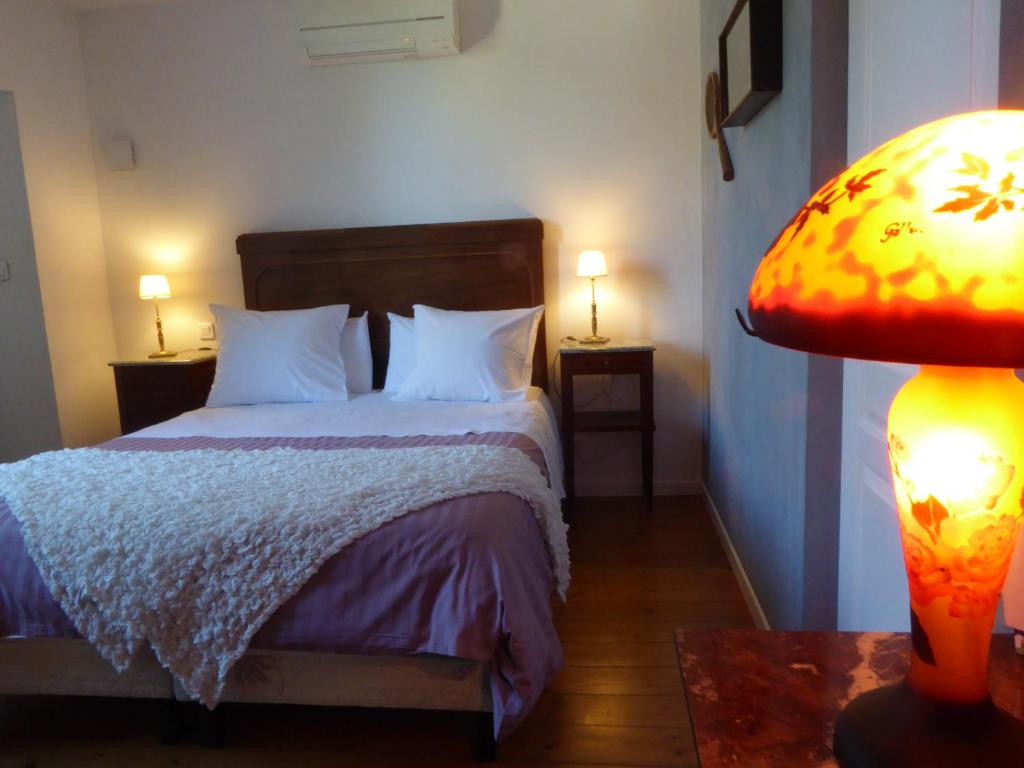 波尔多拉梅森城堡庄园住宿加早餐酒店的一间卧室配有带白色枕头和灯的床