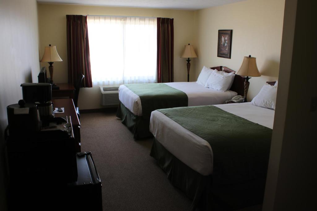 FairburyThe Edgewood Hotel and Suites的酒店客房设有两张床和窗户。