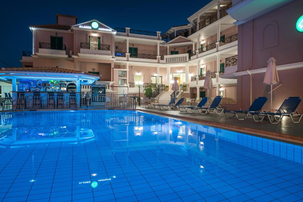蒂锡利维Alamis Hotel & Apartments的夜间在酒店前的游泳池