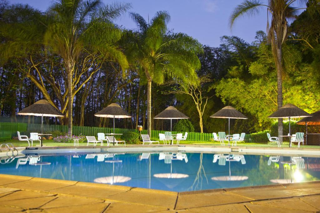 利隆圭太阳鸟首都酒店的一个带椅子和遮阳伞的游泳池