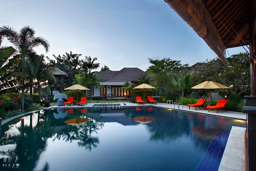 克拉玛斯巴厘岛橙色别墅的一个带橙色椅子和遮阳伞的游泳池