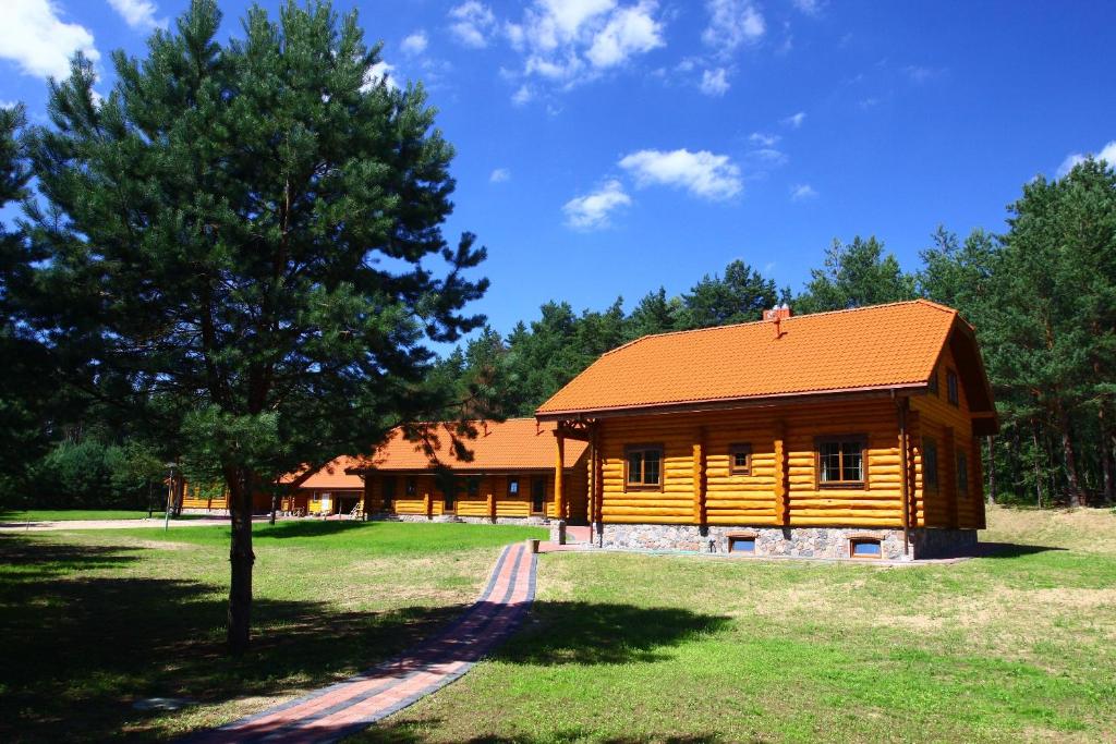 SužionysAsvejos slenis的小木屋,拥有橙色屋顶和树